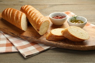 Photo of Cut fresh baguette served on wooden table, closeup