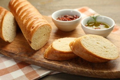 Photo of Cut fresh baguette served on wooden table, closeup