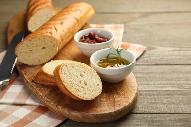 Photo of Cut fresh baguette served on wooden table, closeup