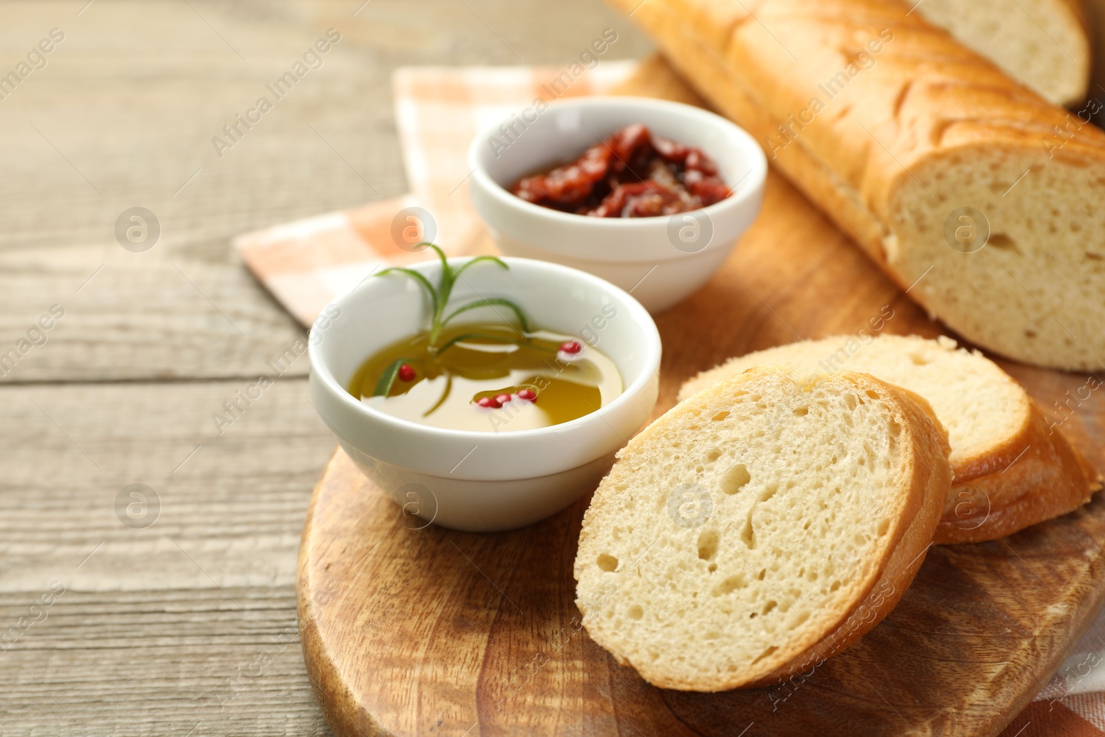 Photo of Cut fresh baguette served on wooden table, closeup