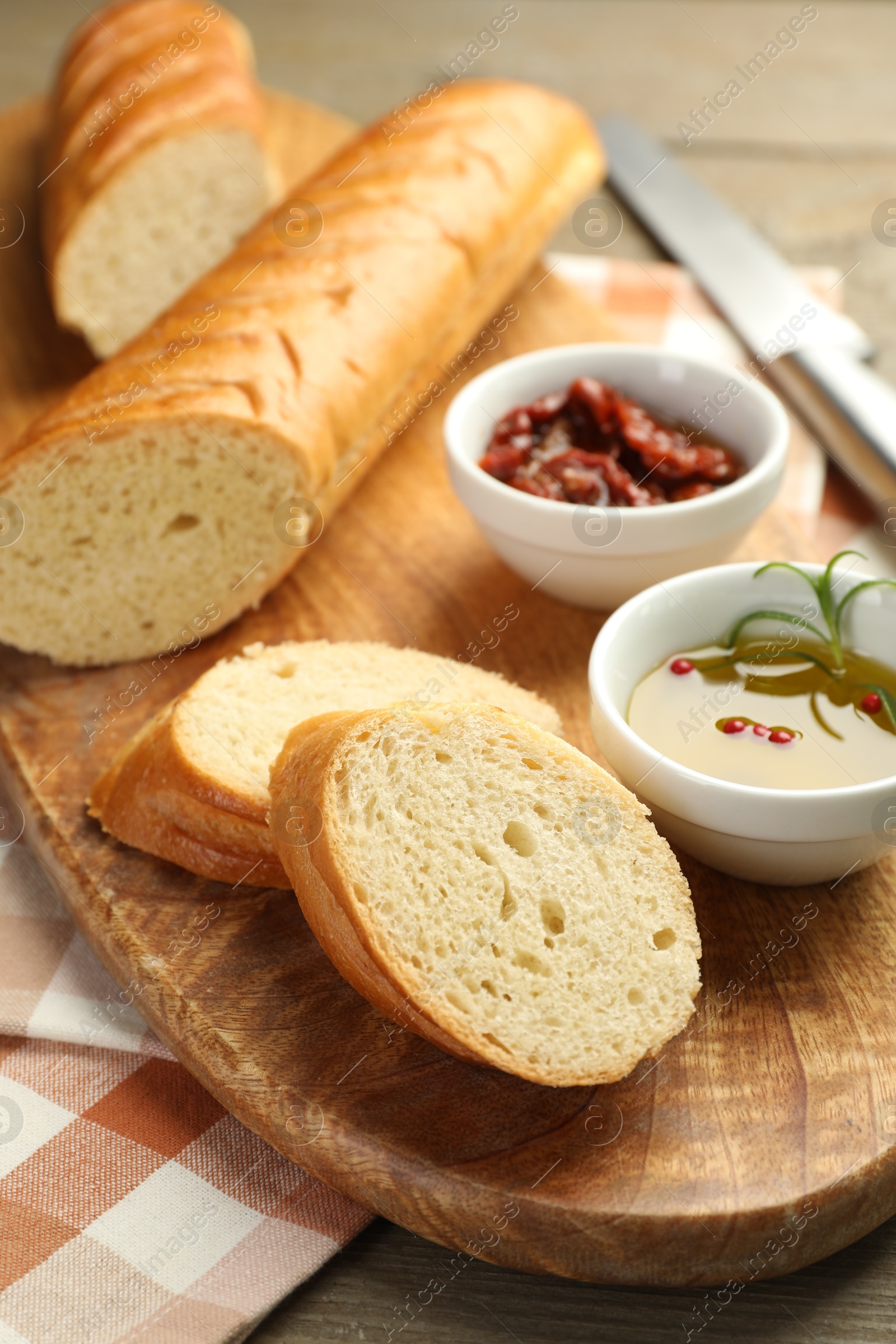 Photo of Cut fresh baguette served on wooden table, closeup