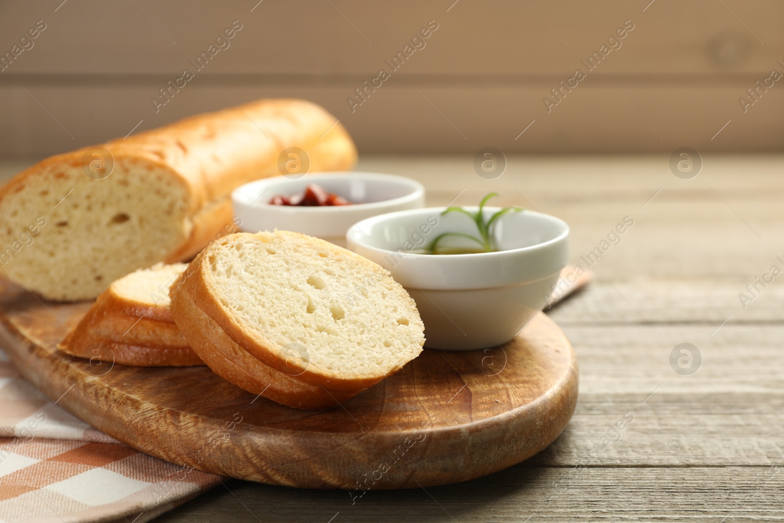 Photo of Cut fresh baguette served on wooden table, closeup