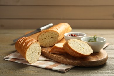 Photo of Cut fresh baguette served on wooden table