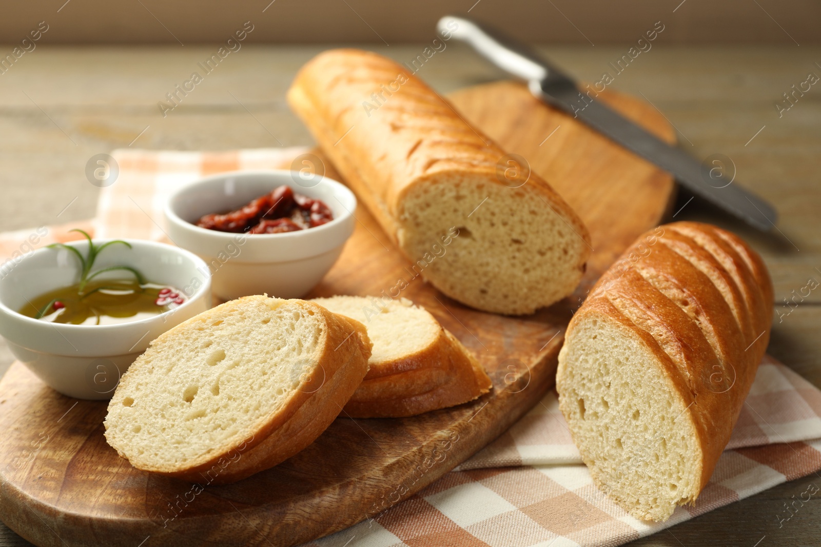 Photo of Cut fresh baguette served on wooden table, closeup