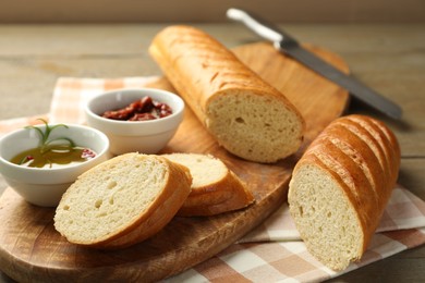 Photo of Cut fresh baguette served on wooden table, closeup