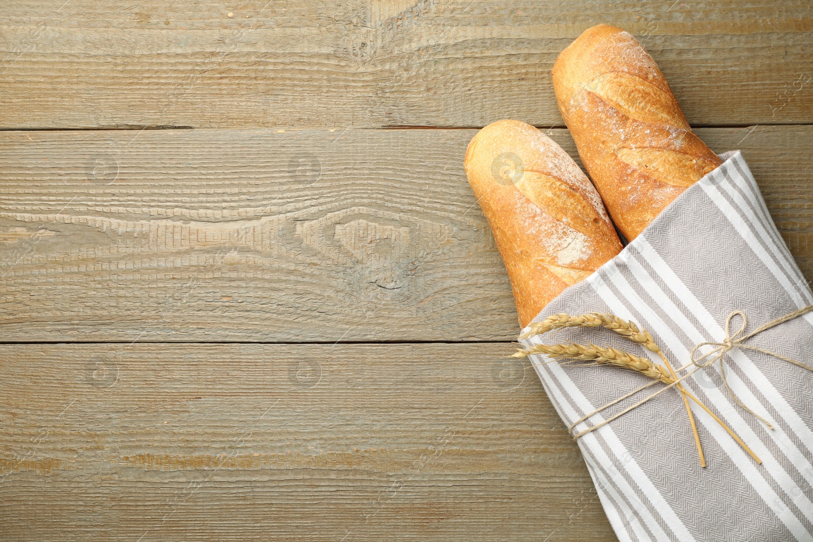 Photo of Fresh baguettes and spikes on wooden table, top view. Space for text