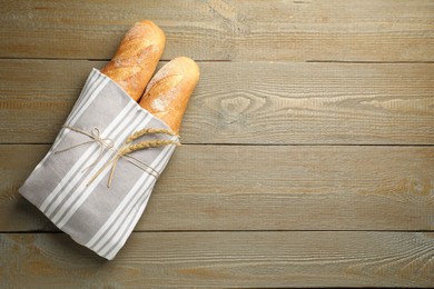 Photo of Fresh baguettes and spikes on wooden table, top view. Space for text