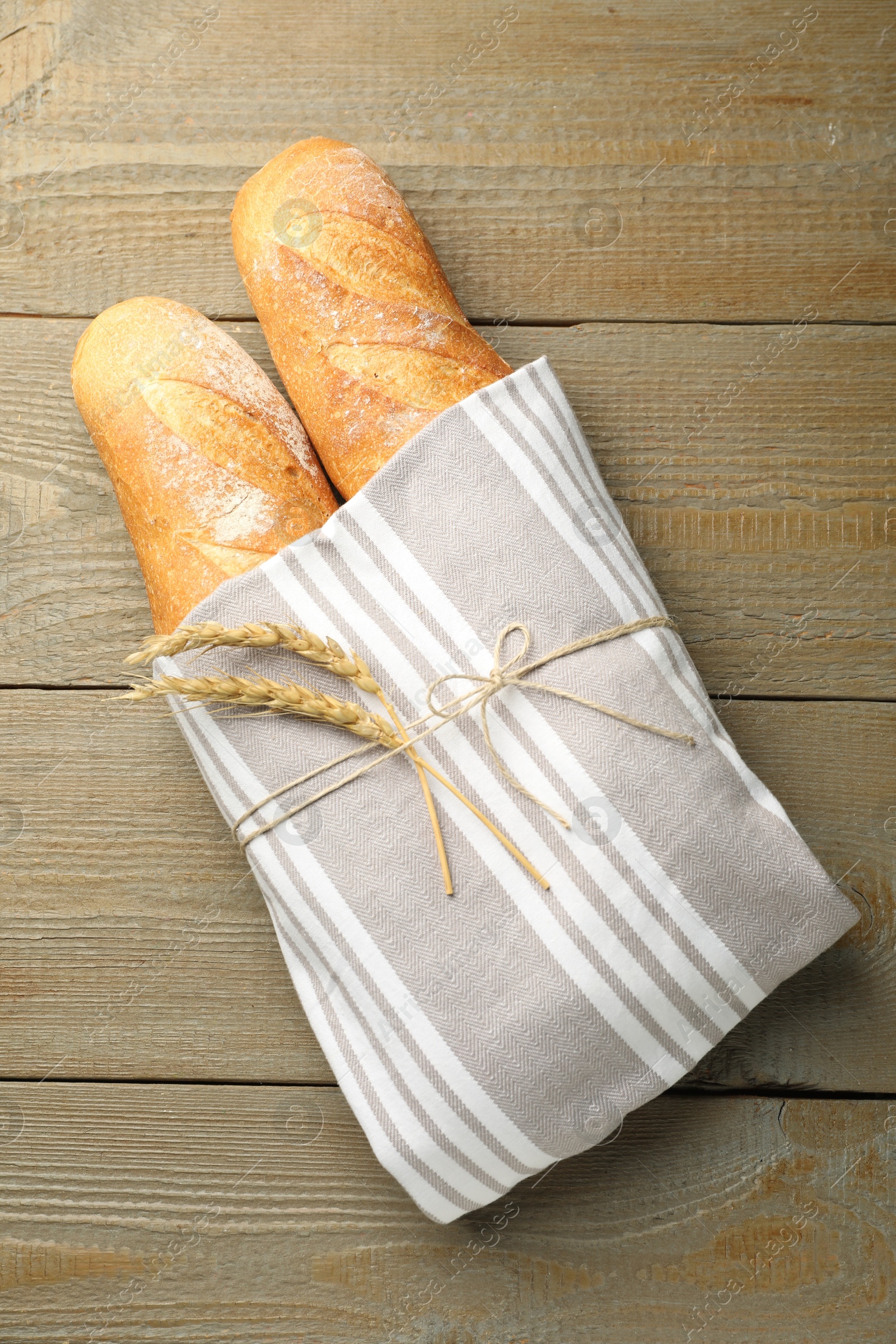 Photo of Fresh baguettes and spikes on wooden table, top view