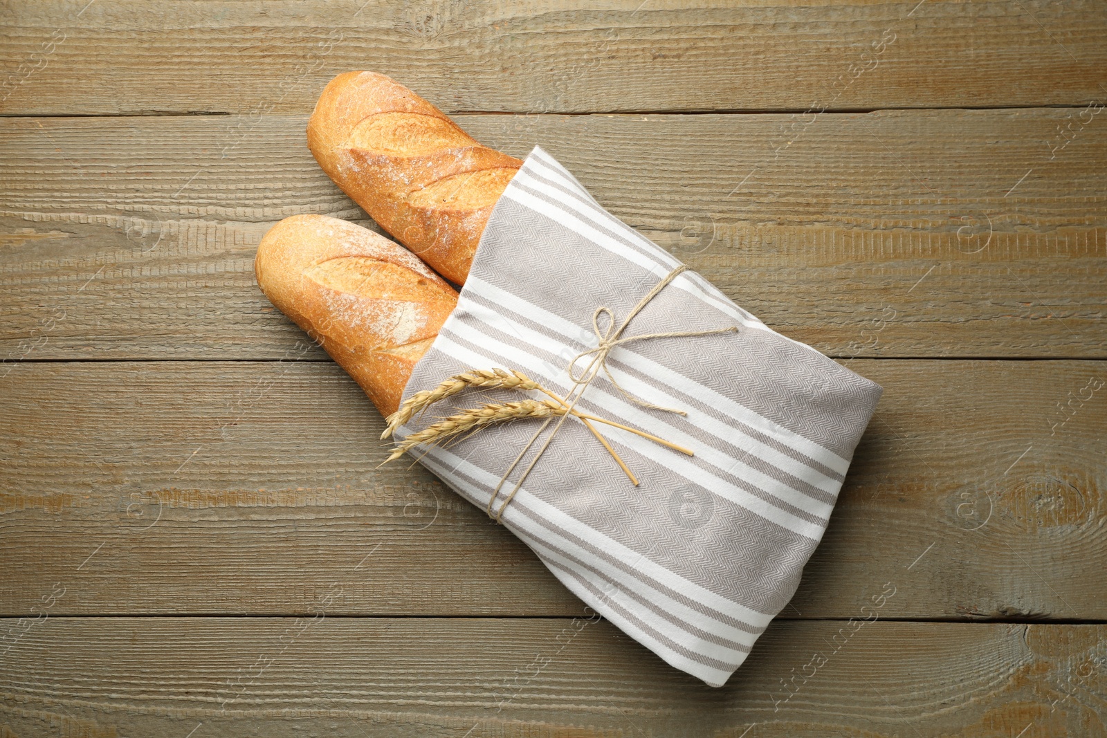 Photo of Fresh baguettes and spikes on wooden table, top view