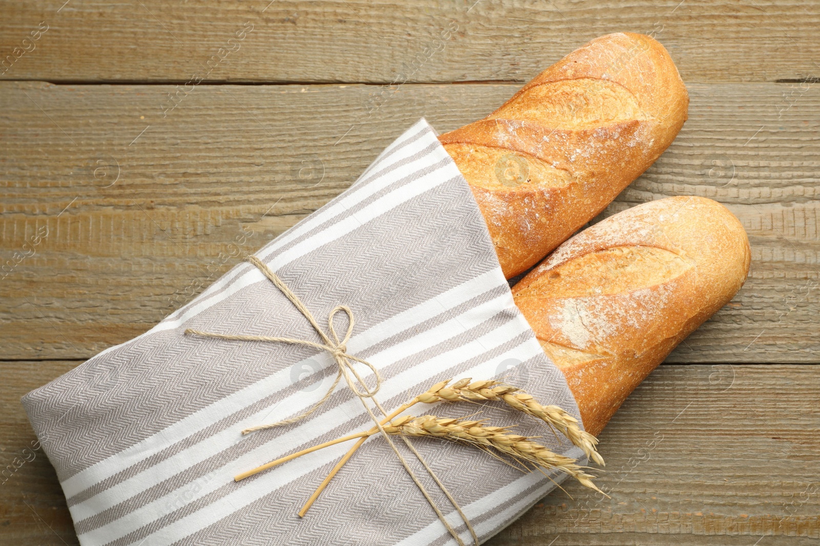 Photo of Fresh baguettes and spikes on wooden table, top view