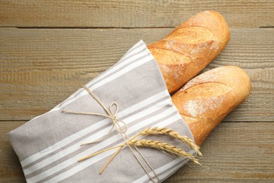 Photo of Fresh baguettes and spikes on wooden table, top view