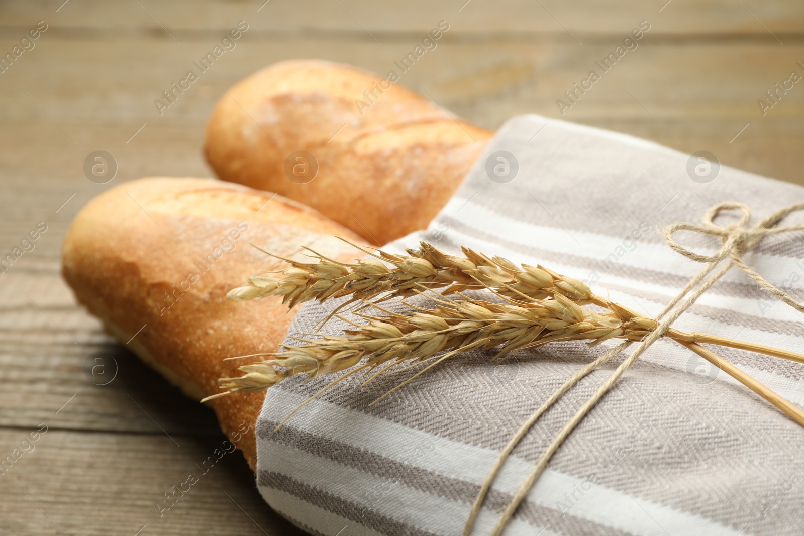 Photo of Fresh baguettes and spikes on wooden table, closeup