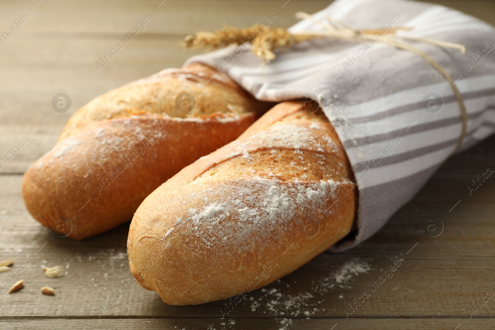 Photo of Freshly baked baguettes on wooden table, closeup