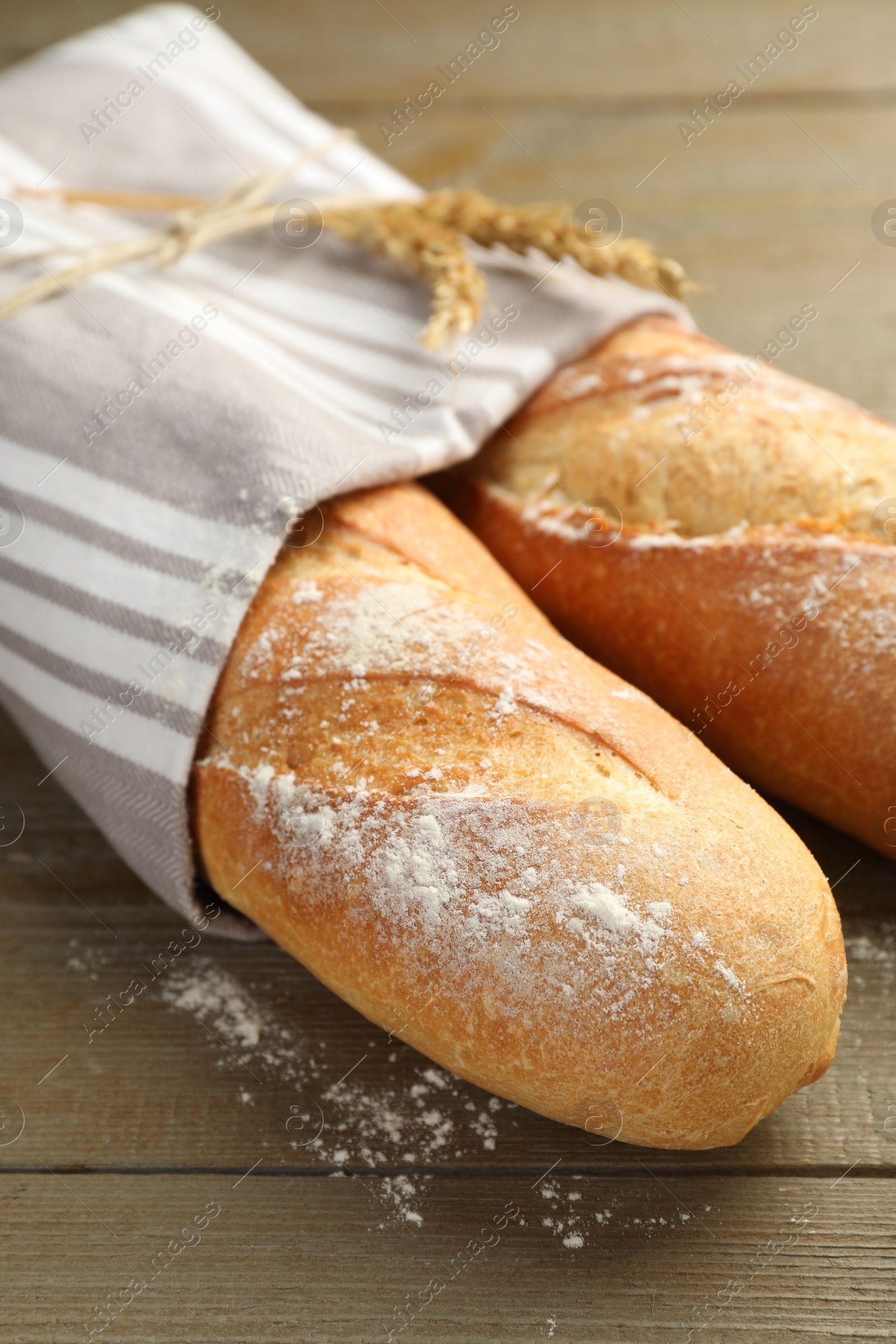 Photo of Freshly baked baguettes on wooden table, closeup