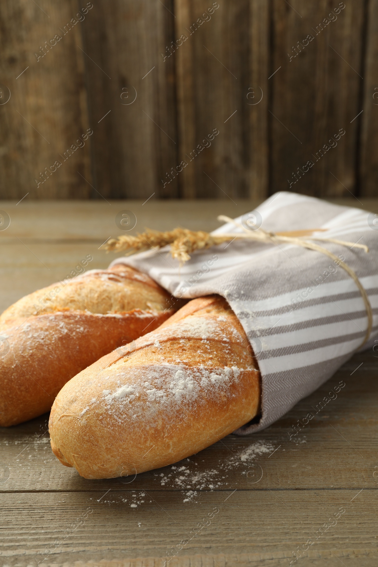 Photo of Freshly baked baguettes on wooden table, closeup