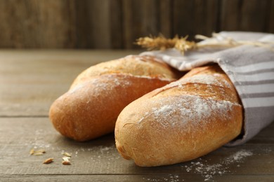 Photo of Freshly baked baguettes on wooden table, closeup