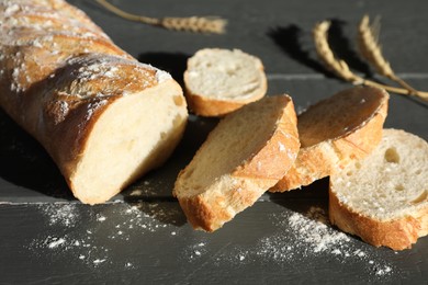 Photo of Pieces of fresh baguette with flour and spikes on grey wooden table