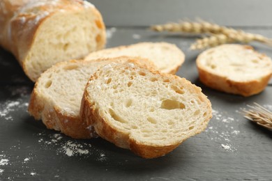 Photo of Pieces of fresh baguette with flour and spikes on grey wooden table, closeup