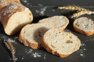 Photo of Pieces of fresh baguette with flour and spikes on grey wooden table, closeup