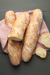 Photo of Cut fresh baguettes on grey wooden table, top view