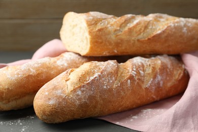 Photo of Cut fresh baguettes on grey wooden table, closeup