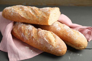 Photo of Cut fresh baguettes on grey wooden table, closeup