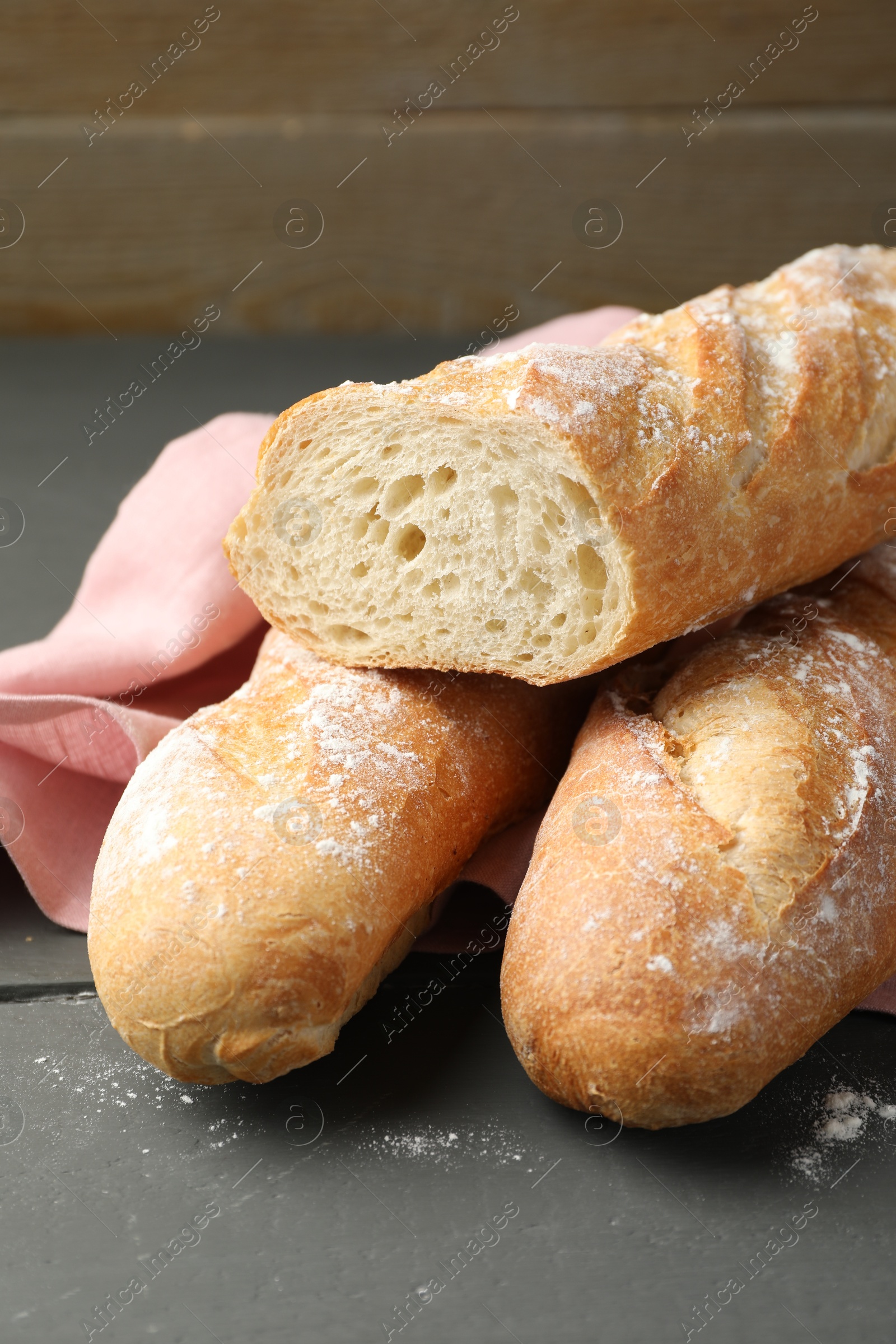 Photo of Cut fresh baguettes on grey wooden table, closeup