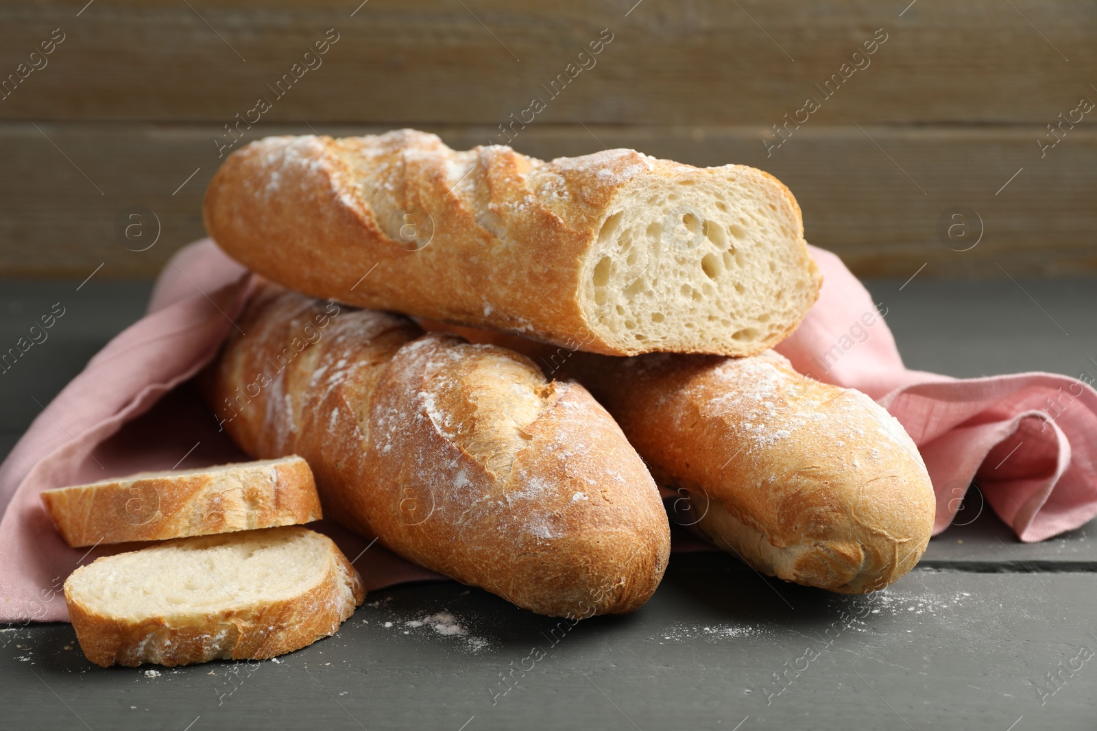 Photo of Cut fresh baguettes on grey wooden table, closeup