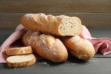 Photo of Cut fresh baguettes on grey wooden table, closeup