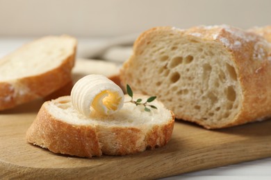 Photo of Cut baguette with butter and herbs on table, closeup