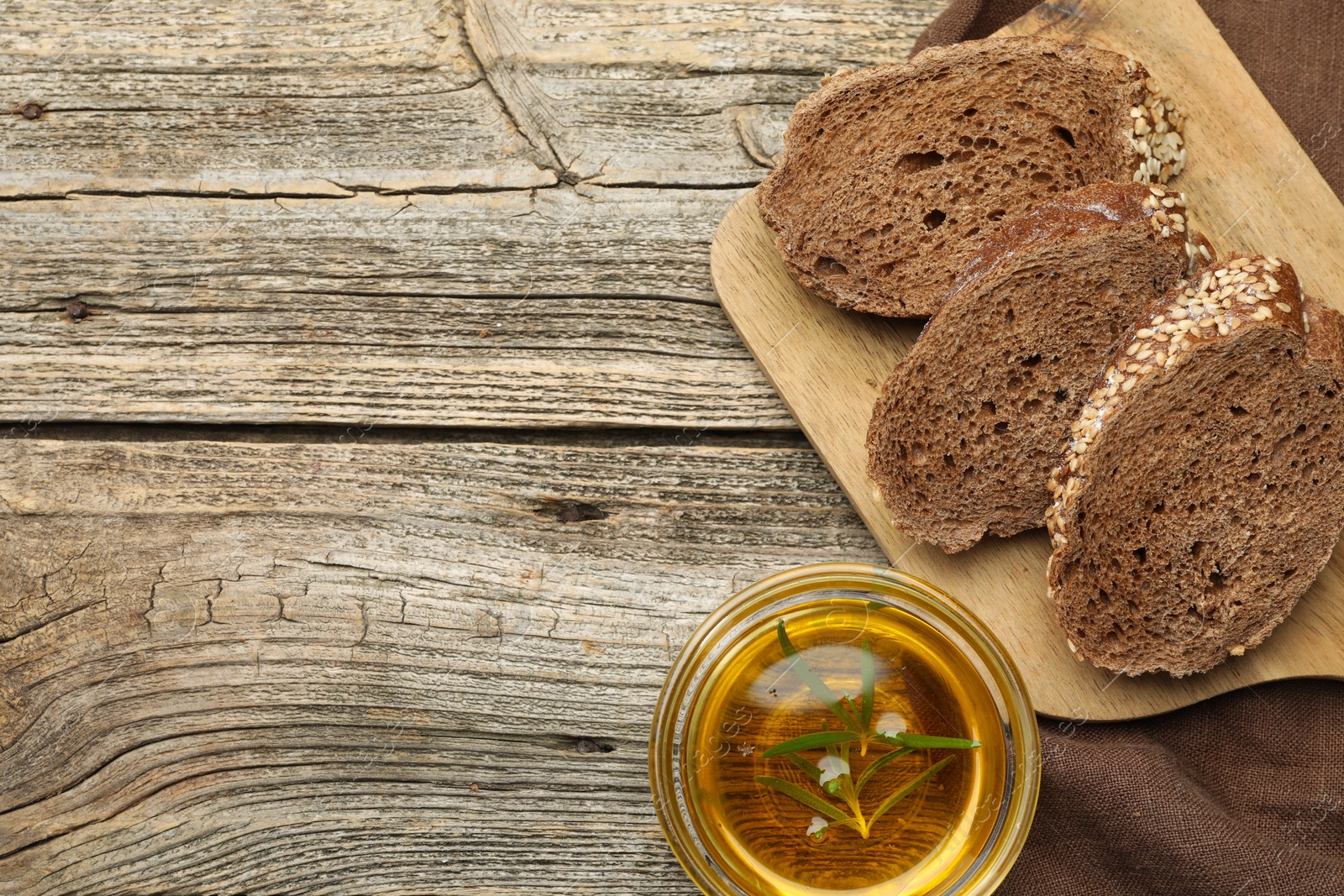 Photo of Slices of rye baguette, oil and garlic on wooden table, flat lay. Space for text