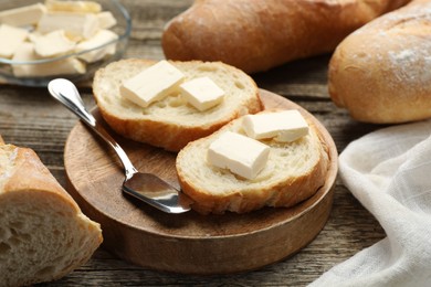 Photo of Slices of fresh baguette with butter on wooden table, closeup