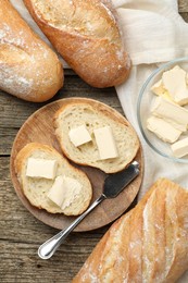 Photo of Slices of fresh baguette with butter on wooden table, flat lay