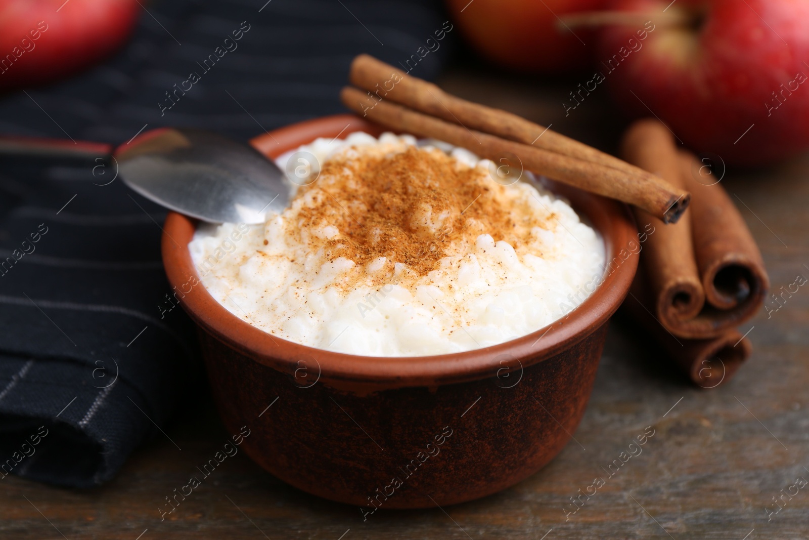 Photo of Delicious rice pudding with cinnamon sticks on wooden table, closeup