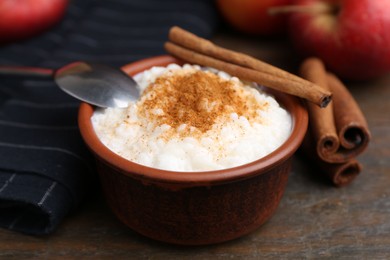 Photo of Delicious rice pudding with cinnamon sticks on wooden table, closeup