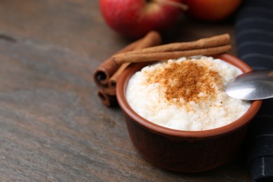 Photo of Delicious rice pudding with cinnamon sticks on wooden table, closeup. Space for text