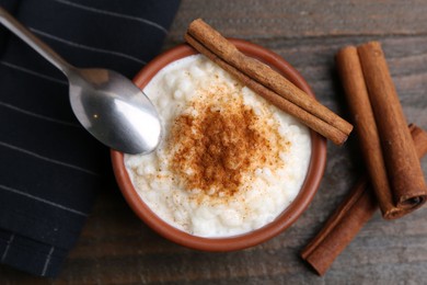 Photo of Delicious rice pudding with cinnamon sticks on wooden table, top view