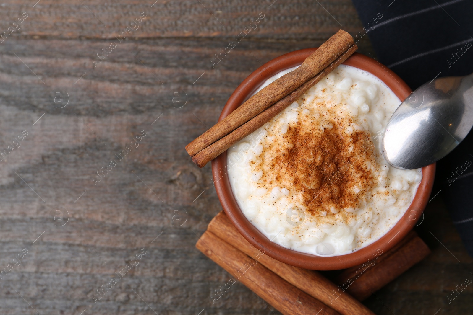 Photo of Delicious rice pudding with cinnamon on wooden table, top view. Space for text