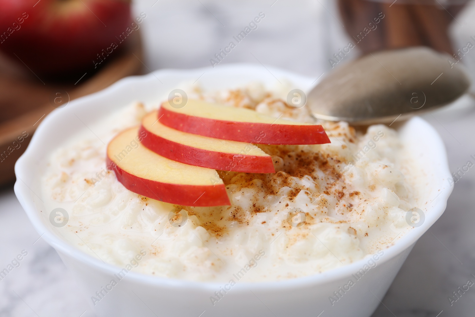 Photo of Delicious rice pudding with cinnamon and apple on table, closeup