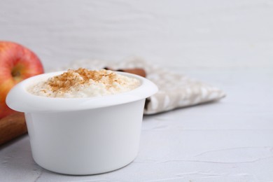 Photo of Delicious rice pudding with cinnamon on white textured table, closeup. Space for text