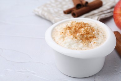 Photo of Delicious rice pudding with cinnamon on white textured table, closeup. Space for text