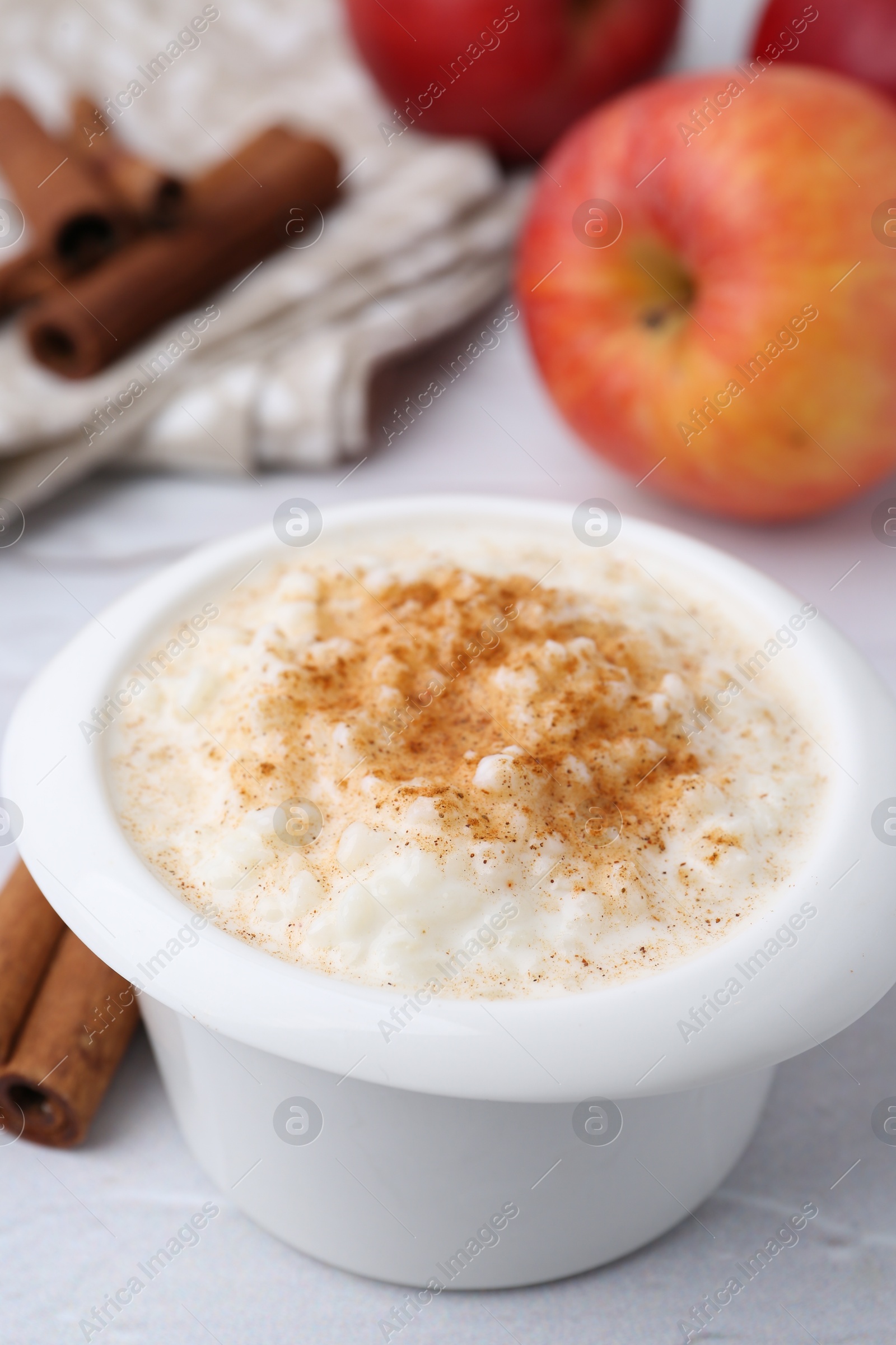 Photo of Delicious rice pudding with cinnamon and apples on white table, closeup