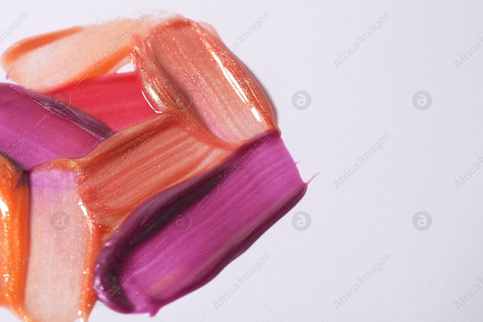 Photo of Samples of different lipglosses on light grey background, closeup. Space for text