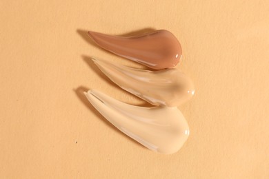 Photo of Samples of different foundations on beige background, top view