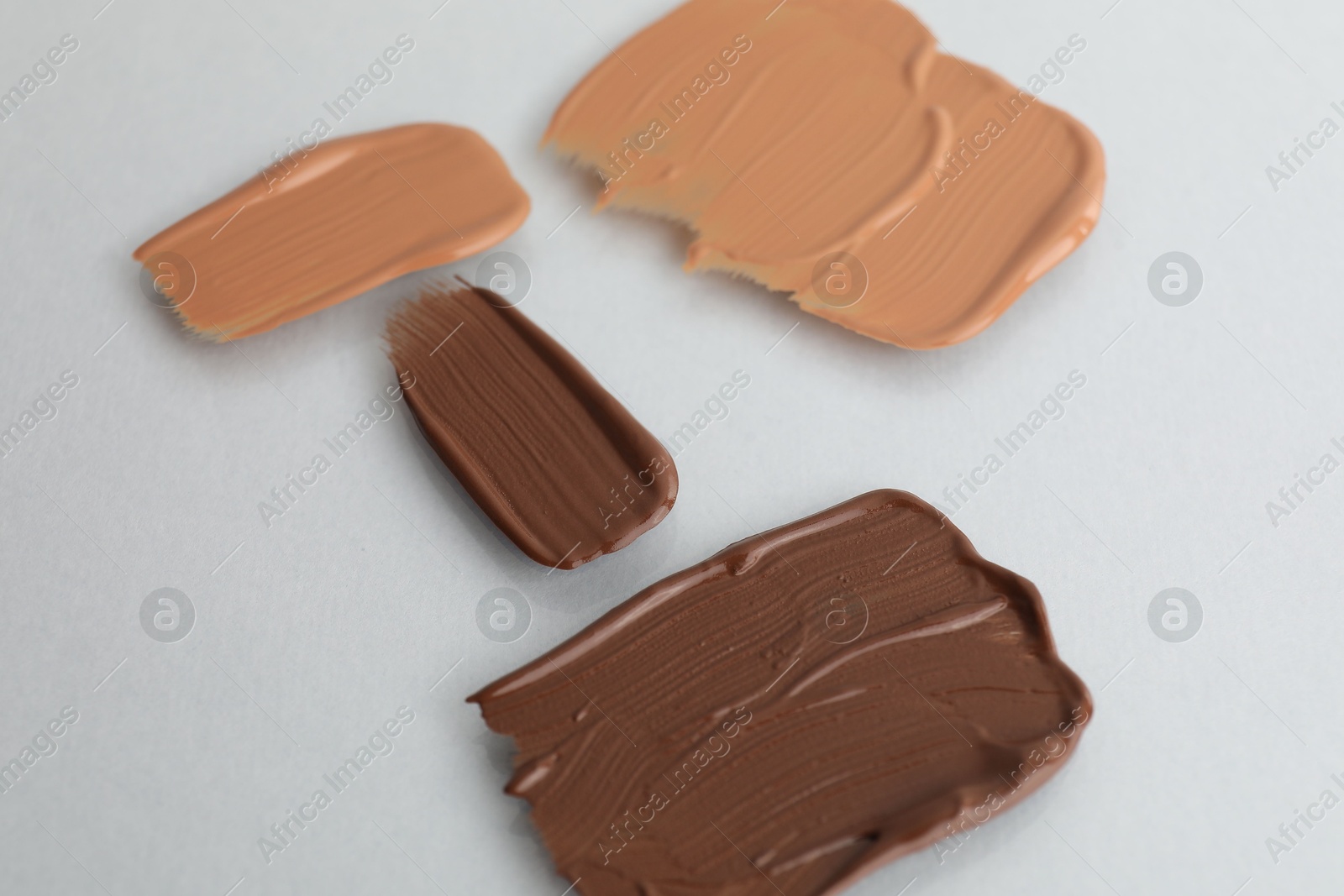 Photo of Samples of different foundations on light grey background, closeup