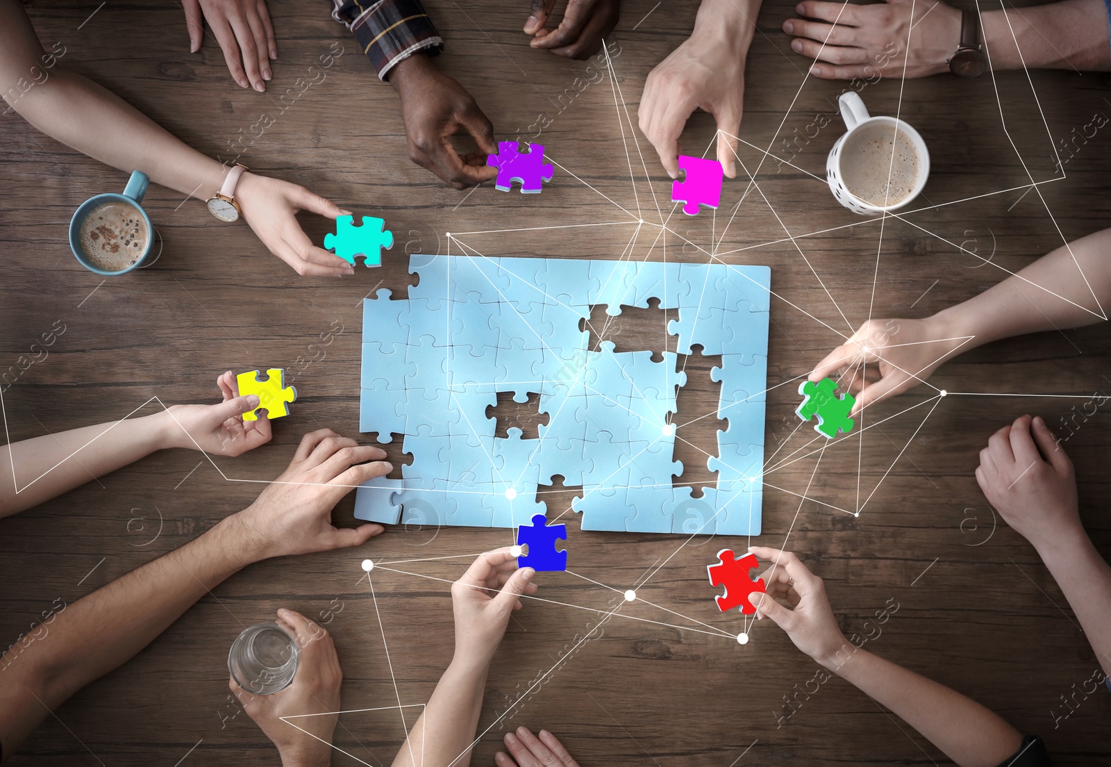 Image of People putting puzzle pieces together on wooden table, top view. Scheme joining them. Concept of partnership