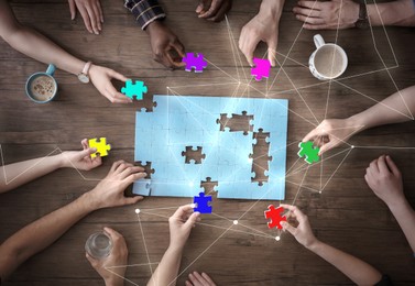 Image of People putting puzzle pieces together on wooden table, top view. Scheme joining them. Concept of partnership