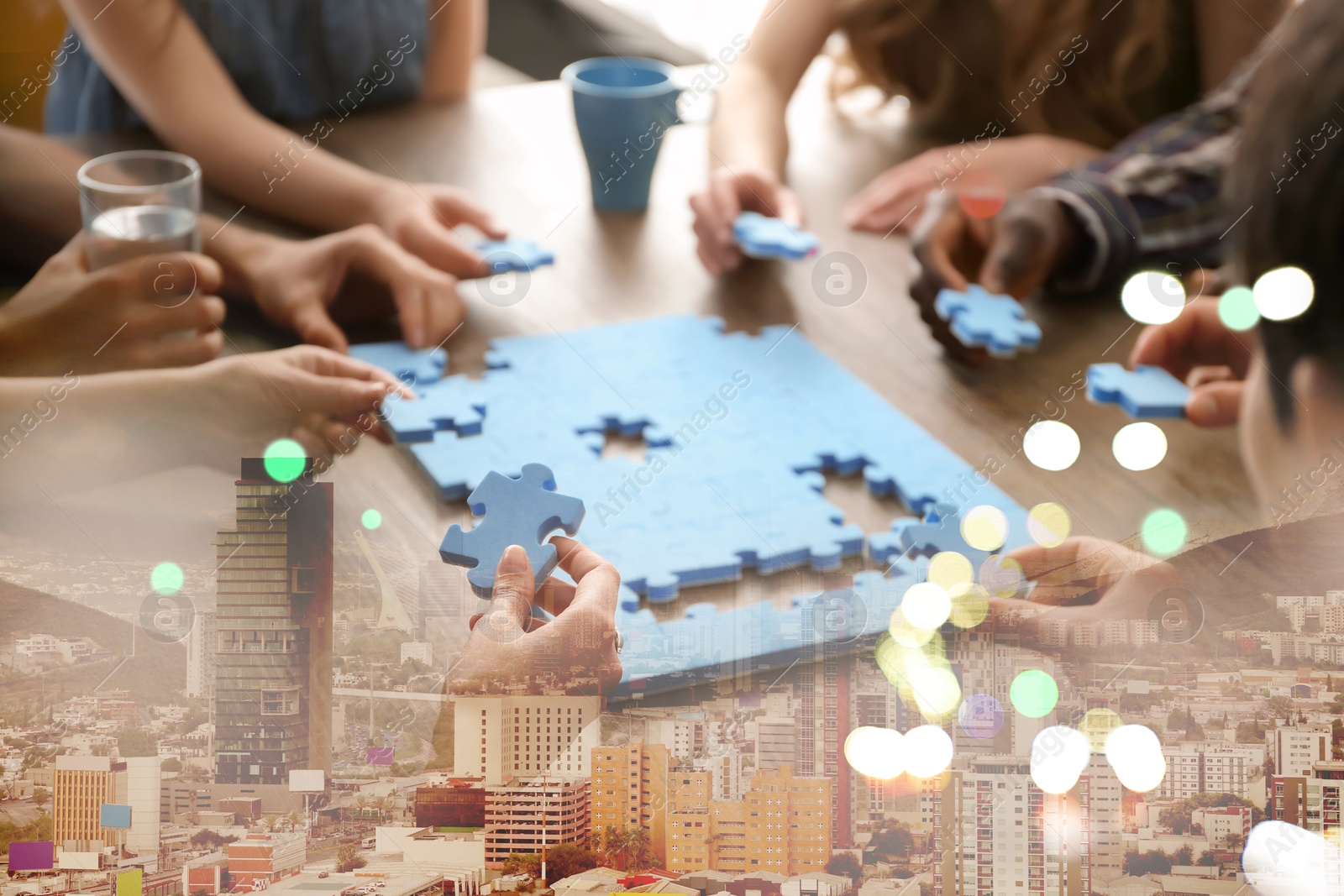 Image of People putting puzzle pieces together on table, double exposure with cityscape. Concept of partnership