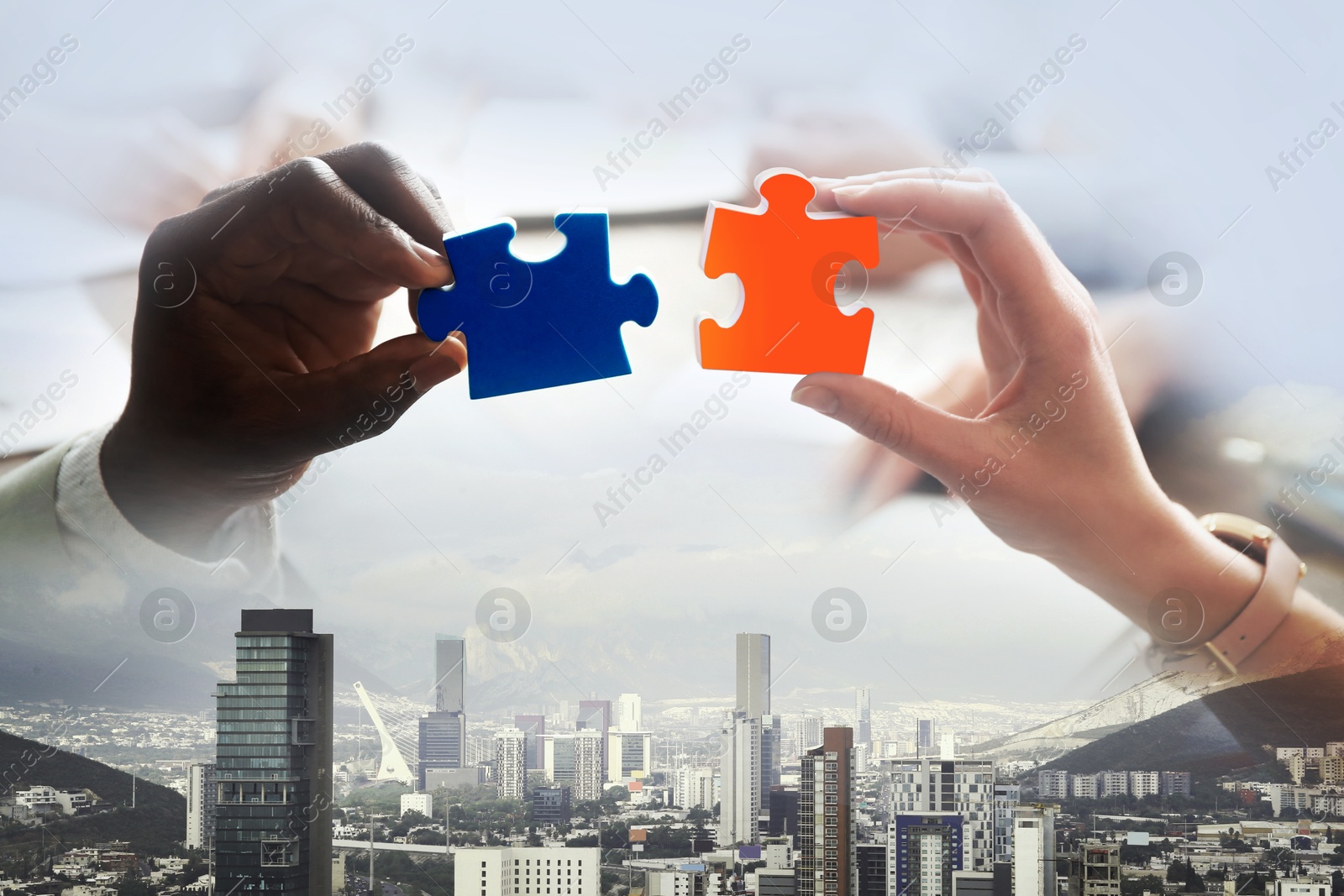 Image of Business partners putting puzzle pieces together, double exposure with cityscape