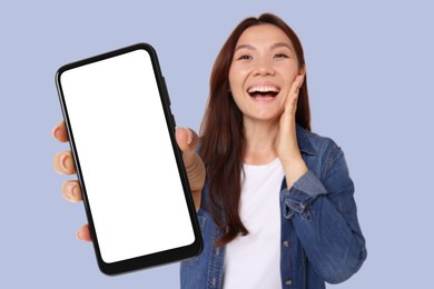 Image of Happy woman showing mobile phone with blank screen against pale blue background